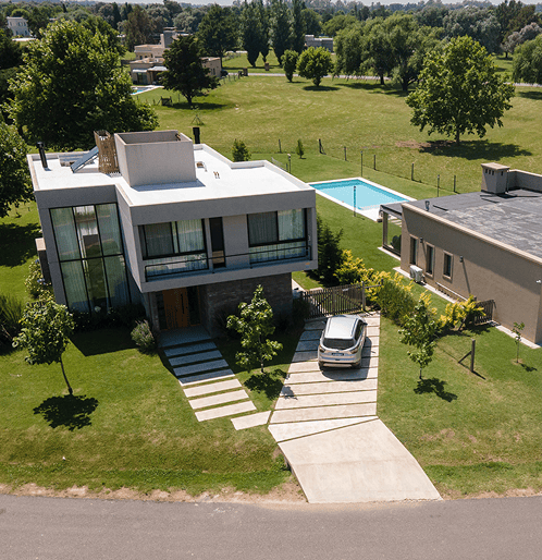 Vista aérea de una casa moderna con piscina y jardín paisajístico.
