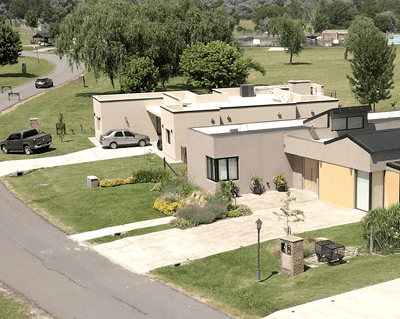Vista aérea de casas modernas con césped verde y coches aparcados.
