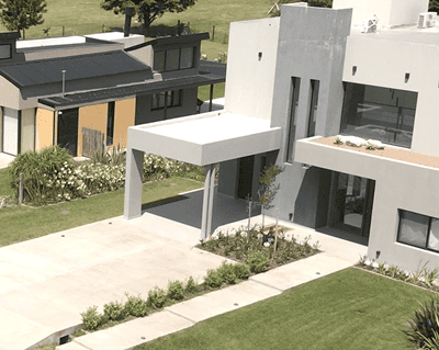 Vista aérea de una casa moderna con jardín paisajístico y entrada para vehículos.