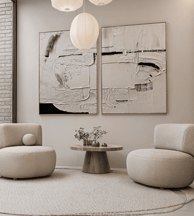 Sala minimalista con dos sillones curvos, mesa redonda y cuadros abstractos en tonos neutros.